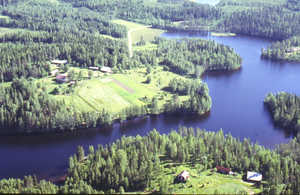 Kuusjärvi ja samanniminen kantatila näkyy vasemmalla ylhäällä, alhaalla tilan entinen torppa Salmenmäki. Ilmakuva vuodelta 1990.